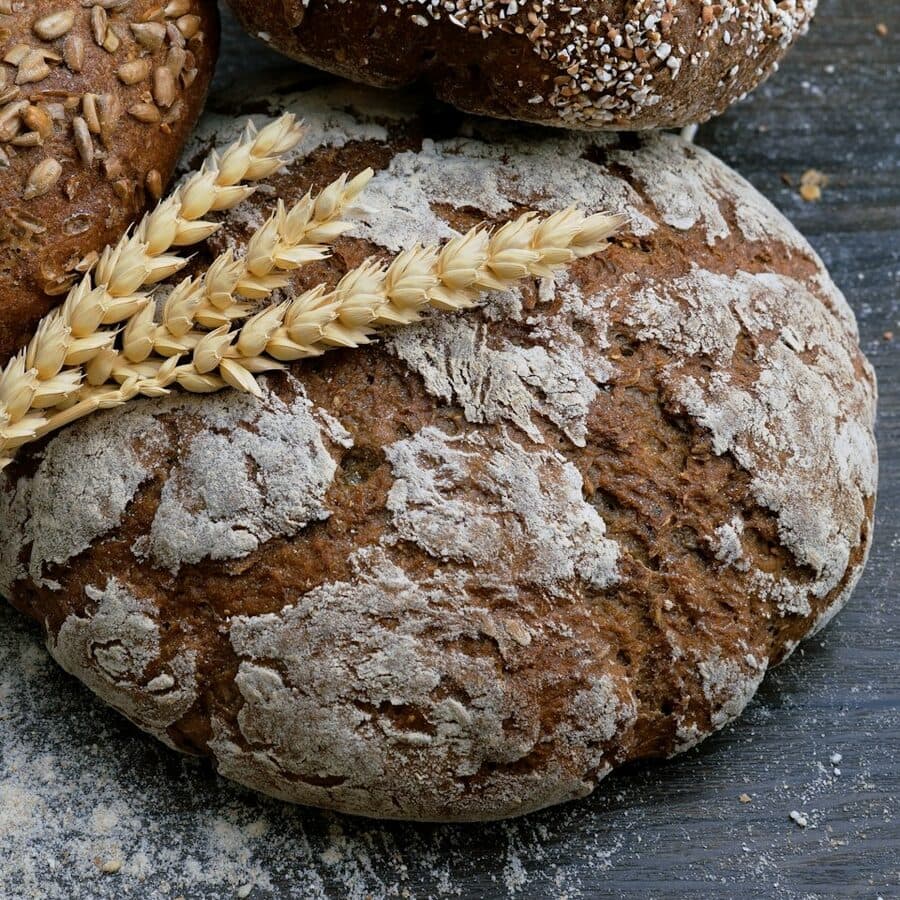 A floured country sourdough loaf with ears of wheat